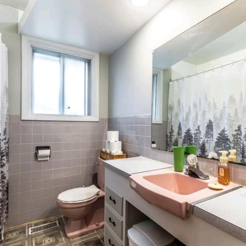 Bathroom before renovation with a pink sink and toilet and dated wall tile