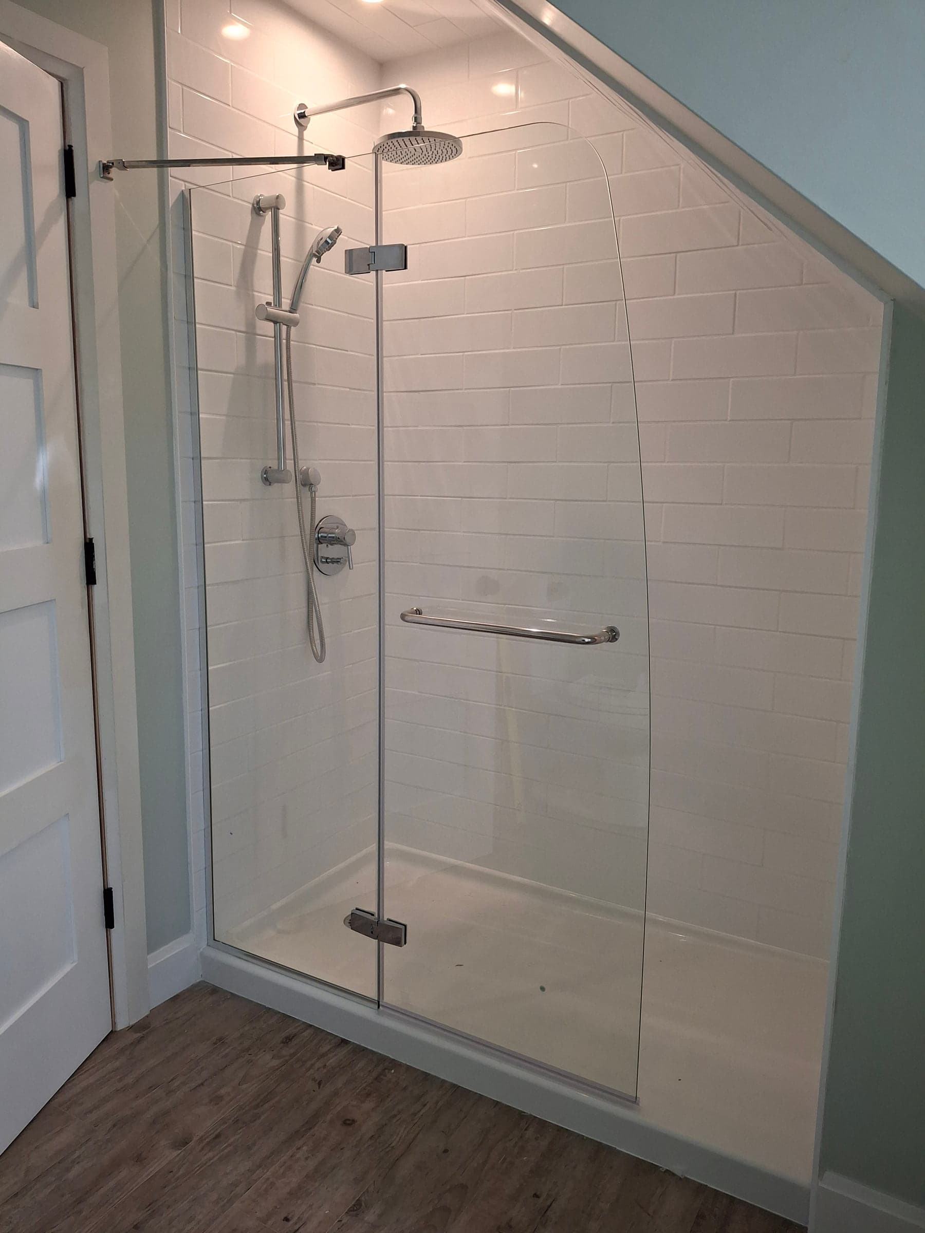 Finished shower with light tile, glass enclosure, and dark fixtures