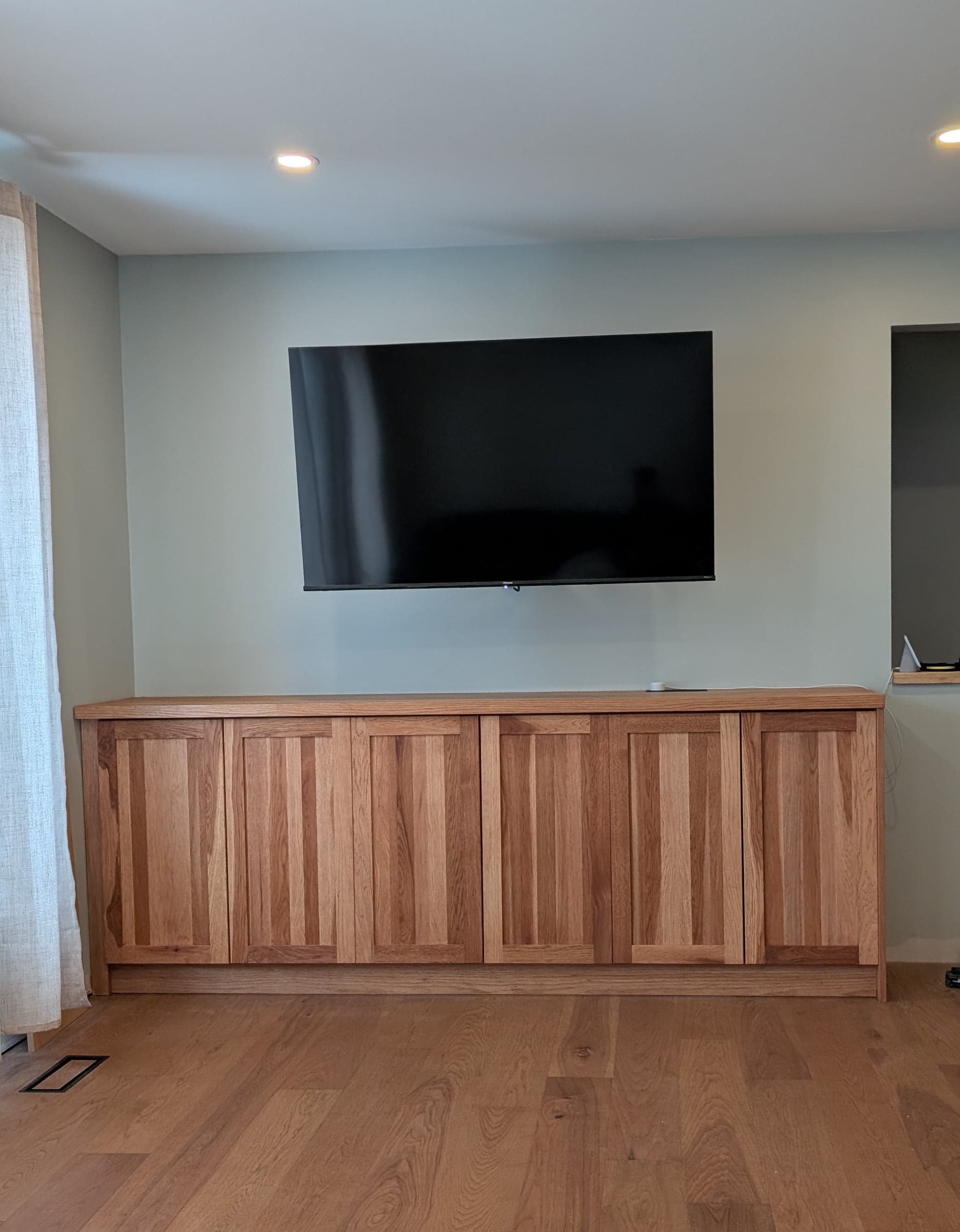Wide view of a wood media cabinet against a light wall