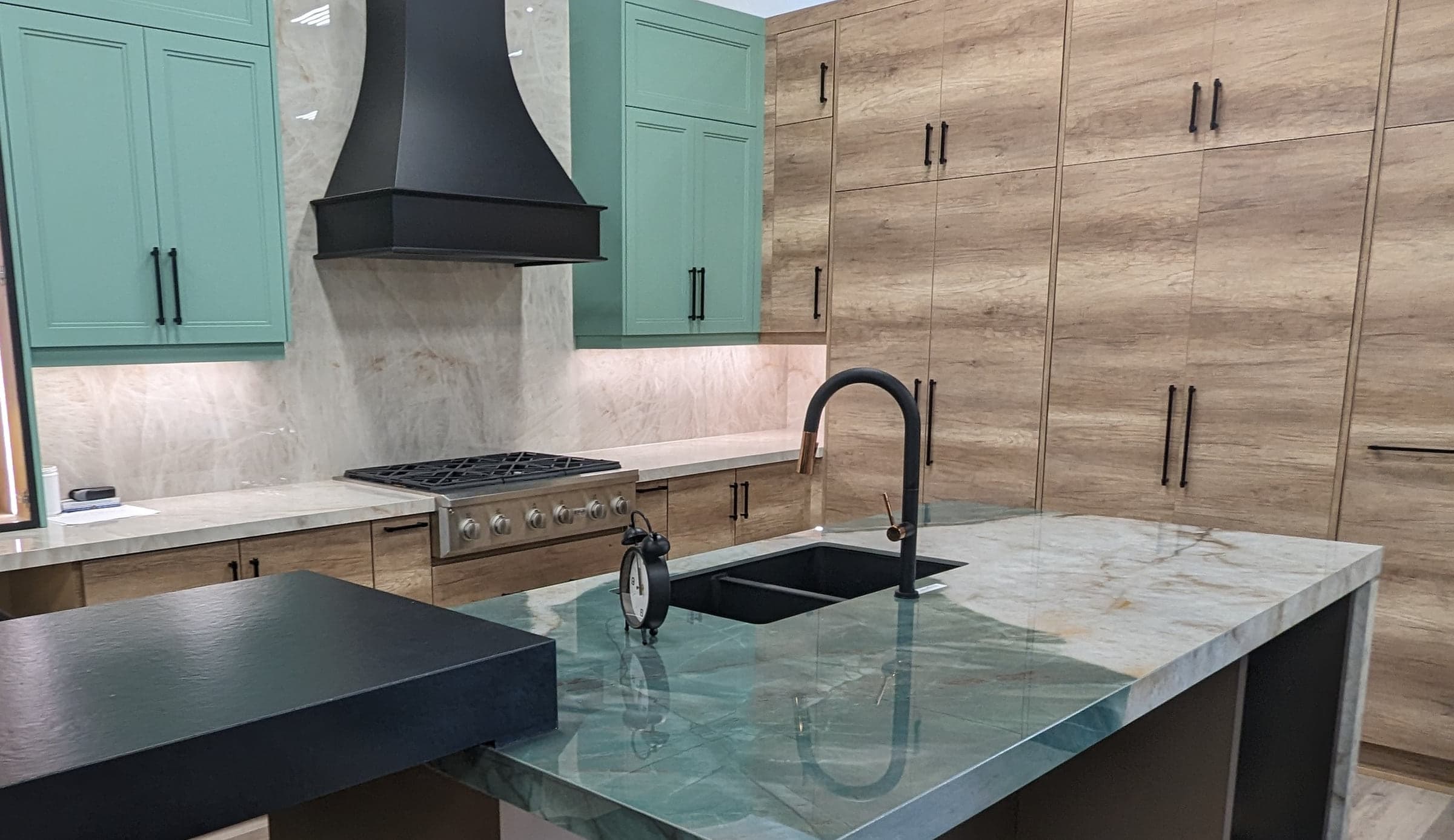 Teal kitchen island facing a stainless range and white cabinetry